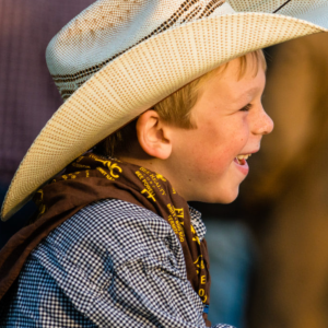 A side profile photo of a smiling young cowboy